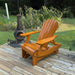 Royal Reclining Glider on a wooden deck with a garden and fire pit in the background - golden glossy