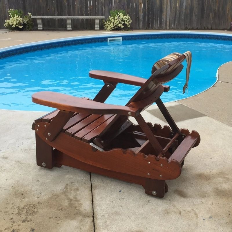 Royal Reclining Glider by a pool with flowers in the background