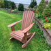 Royal Rocking Adirondack Chair (Large) in a garden setting with flowers and greenery.