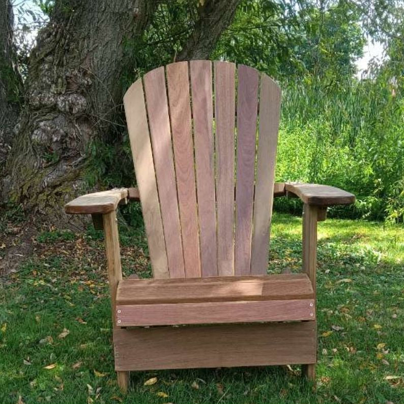 Royal Upright Adirondack Chair, in a garden setting with trees and grass.