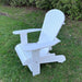 White Royal Upright Adirondack Chair, on a grassy area with greenery in the background