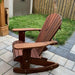 Royal Rocking Adirondack Chair (Large) on a patio with grass and a wooden fence in the background