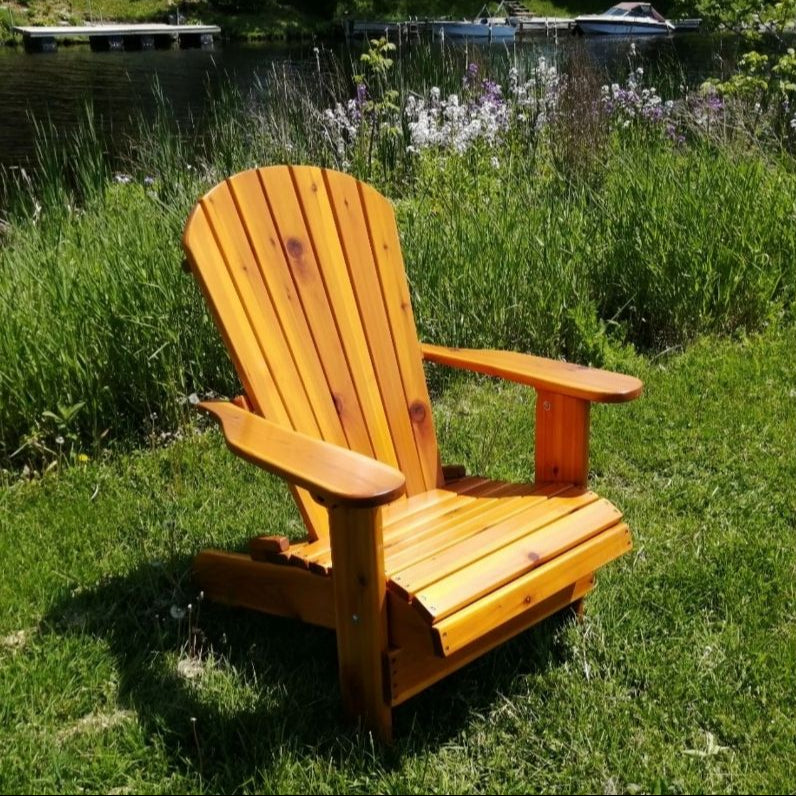 Royal Upright Adirondack Chair, in a grassy area with a lake and boats in the background