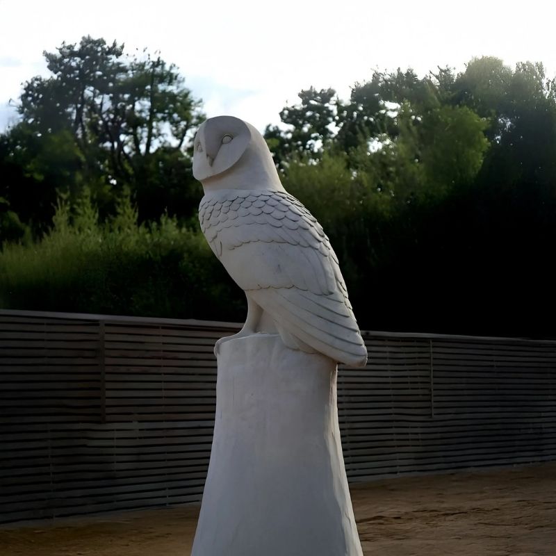 Watchful Owl Marble Outdoor Sculpture outdoor setting with trees on the background