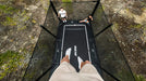 Person standing on a trampoline in a forested area