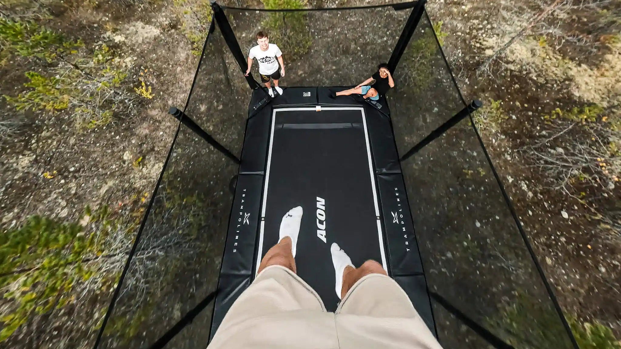 Person standing on a trampoline in a forested area